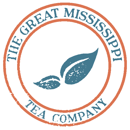 Great Mississippi Tea Company's logo which is a white circle outlined in orange with a light blue tea leaf, big leaf on the right and a smaller leaf on the left, in the middle of the circle, and The Great Mississippi around the top and Tea Company around the bottom
